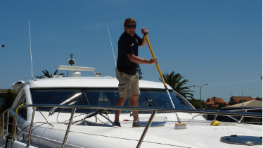 Picture of yacht cleaning service scrubbing the bow of yacht in Florida.