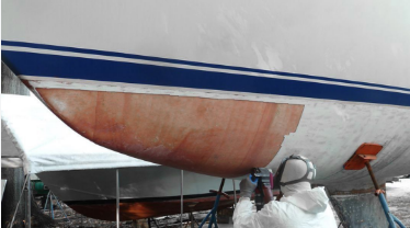 Fiberglass expert cuts away old worn hull bottom to be replaced with new fiberglass layers and gelcoat.