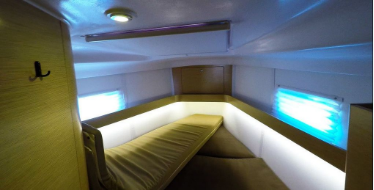Picture of the v berth of a yacht with custom green color upholstery design with lounge.
