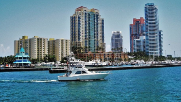 Photo of the Miami Harbor with the skyline in the background and a yacht passing by in August.