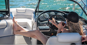 Woman relaxing in the helm seat of a cleaned boat with a beverage in hand off the cost of Miami.