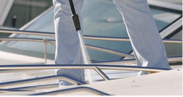 A trained boat cleaner spraying down the top deck of a yacht in Miami.